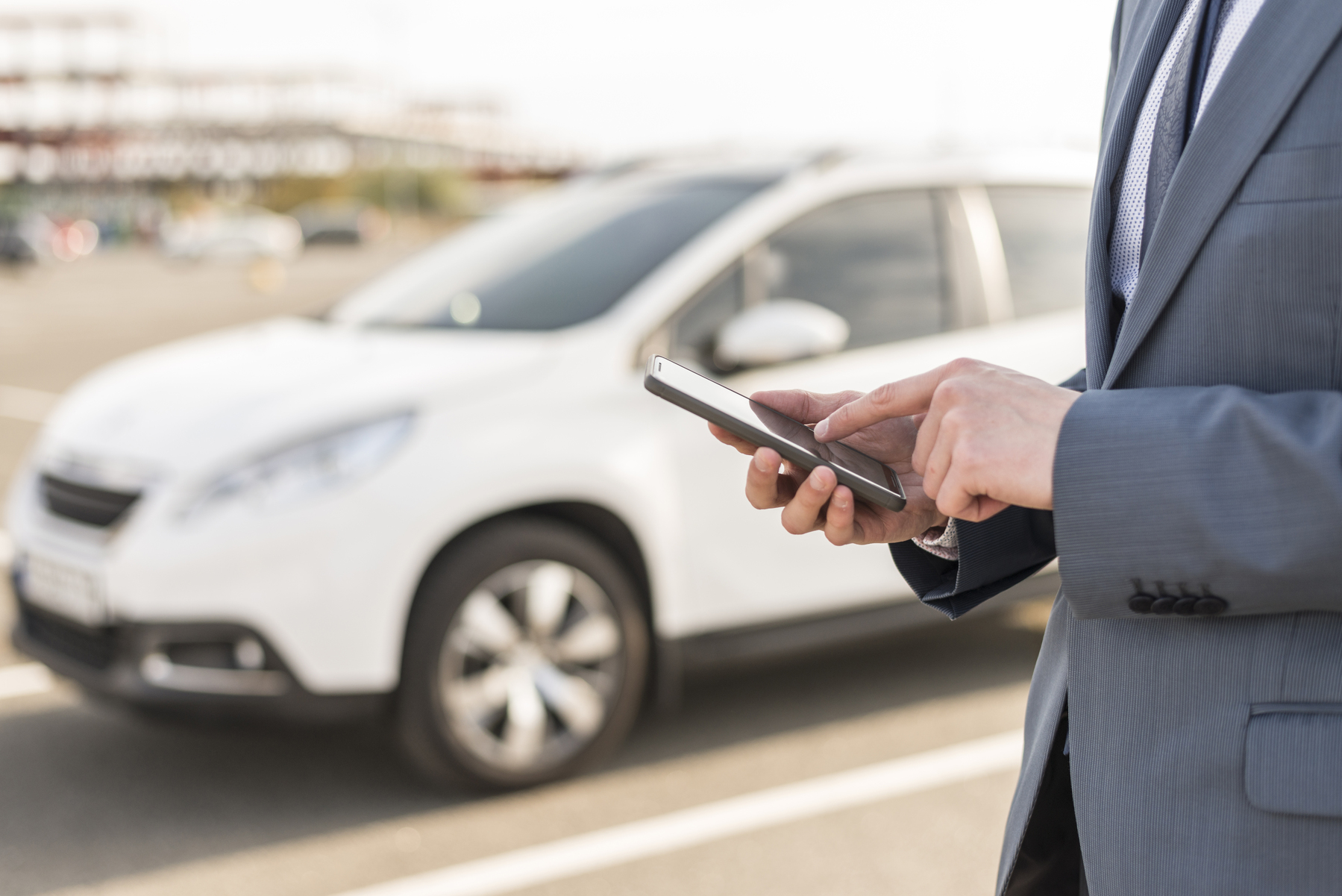 businessman with smartphone in front of car 1